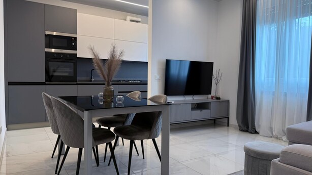 A modern kitchen with a dining area, a flat-screen TV, and a large window with curtains. - Modern apartment in the center 700 meters from the shores of Lake Garda (Desenzano del Garda)