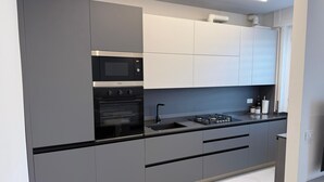 A modern kitchen with grey cabinetry, a built-in oven, a microwave, and a gas stove. - Modern apartment in the center 700 meters from the shores of Lake Garda (Desenzano del Garda)