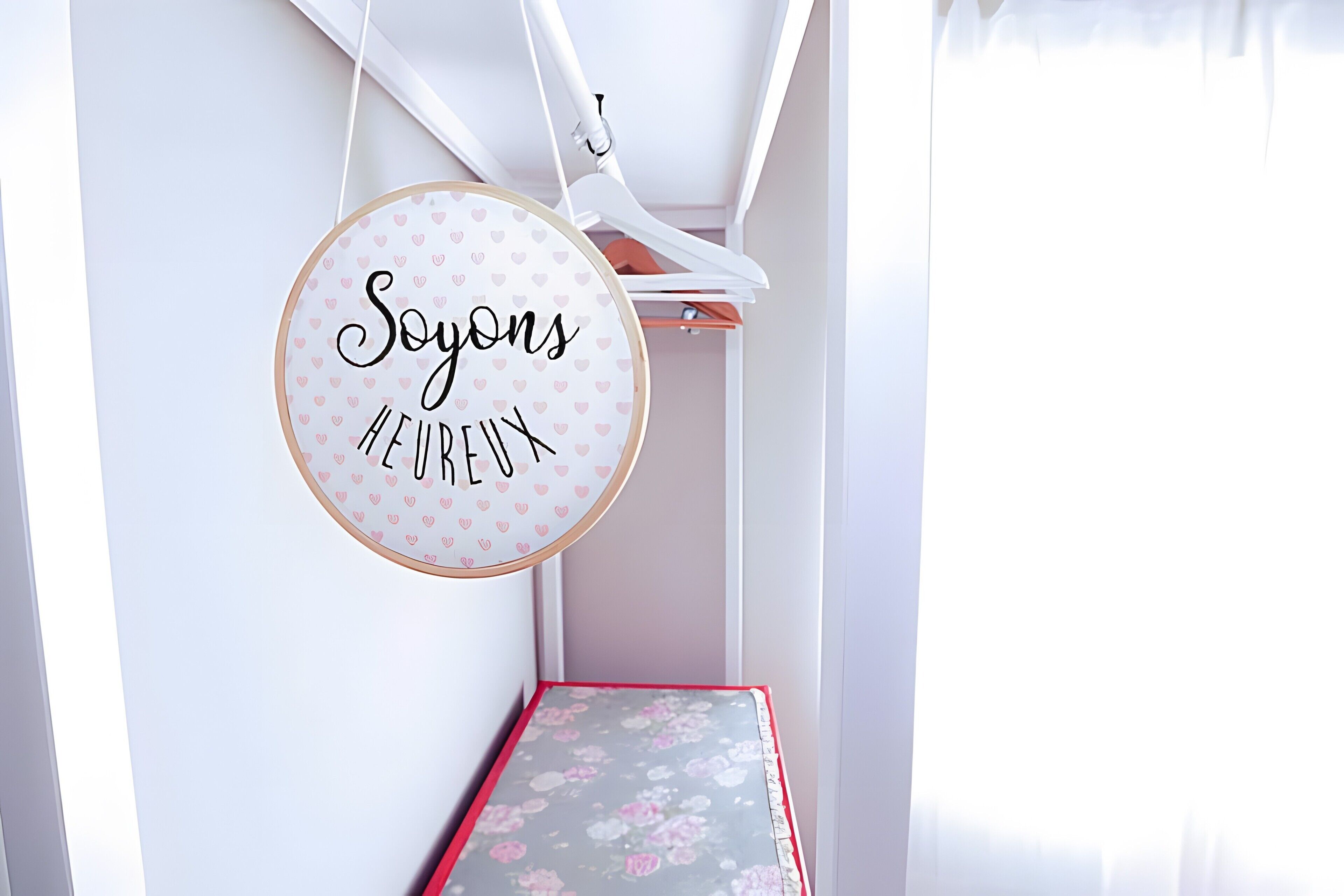Una señal circular con texto, una pared blanca y un objeto con marco rojo sobre una mesa.