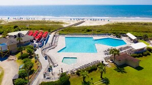 Un resort con una piscina grande, sombrillas de playa y vista al océano.