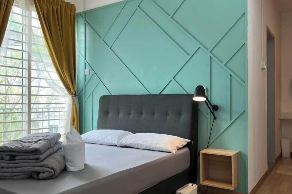 A neatly made bed with pillows and a folded blanket, a bedside lamp, and a small wooden nightstand.