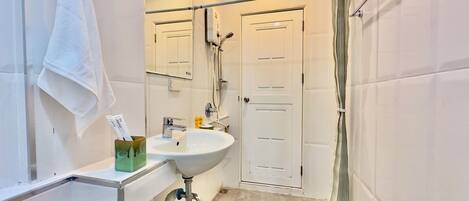 A modern bathroom with a white sink, mirror, and shower curtain.