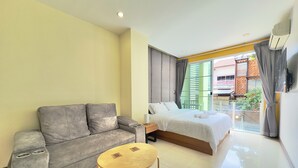 Una habitación de hotel moderna con un sofá, una cama, una pequeña mesa de madera y vistas al exterior.
