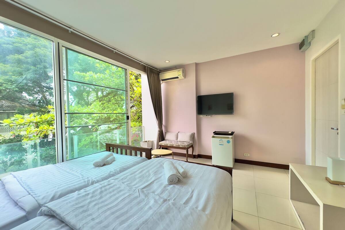 Ein Hotelzimmer mit zwei Betten, einem Sessel, einem Fernseher und einer Minibar.