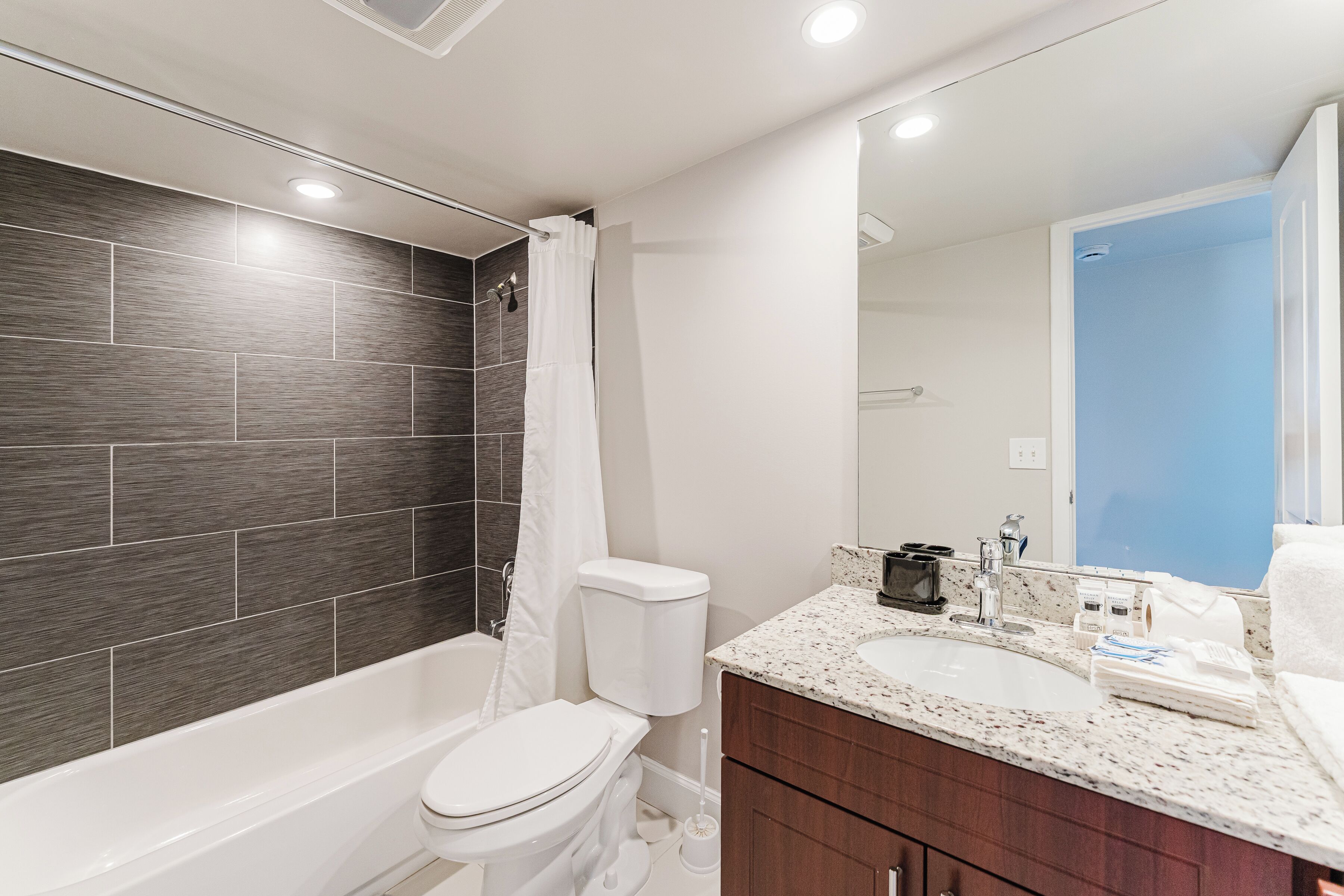 A modern bathroom with a bathtub, toilet, and vanity with a sink.