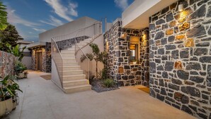 A modern house with a stone exterior, a staircase, and potted plants.