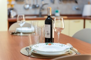 Une table à manger dressée avec une assiette, des verres à vin et une bouteille de vin.