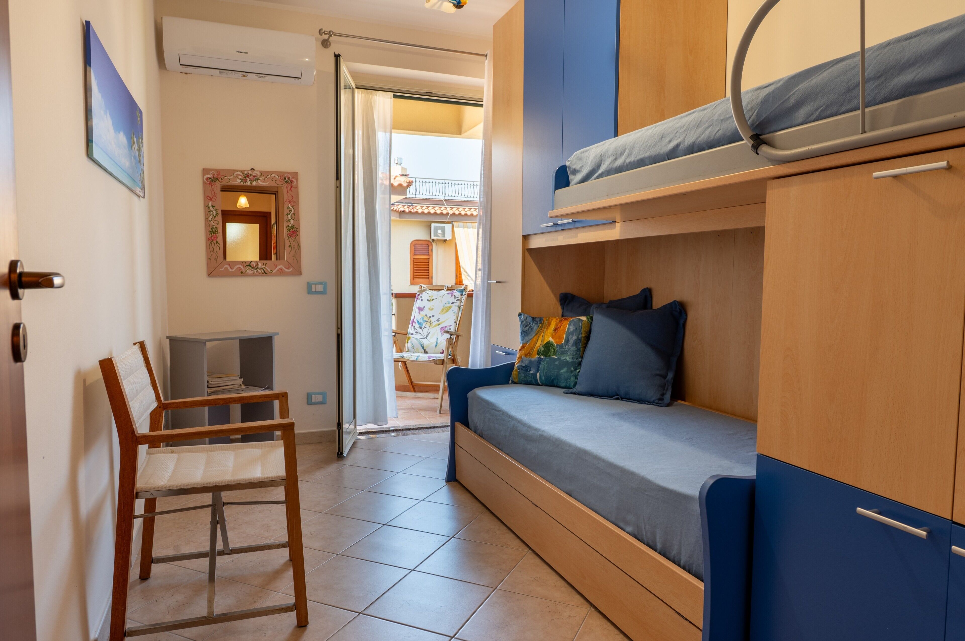 Una habitación pequeña con una cama litera, una silla y una mesita.