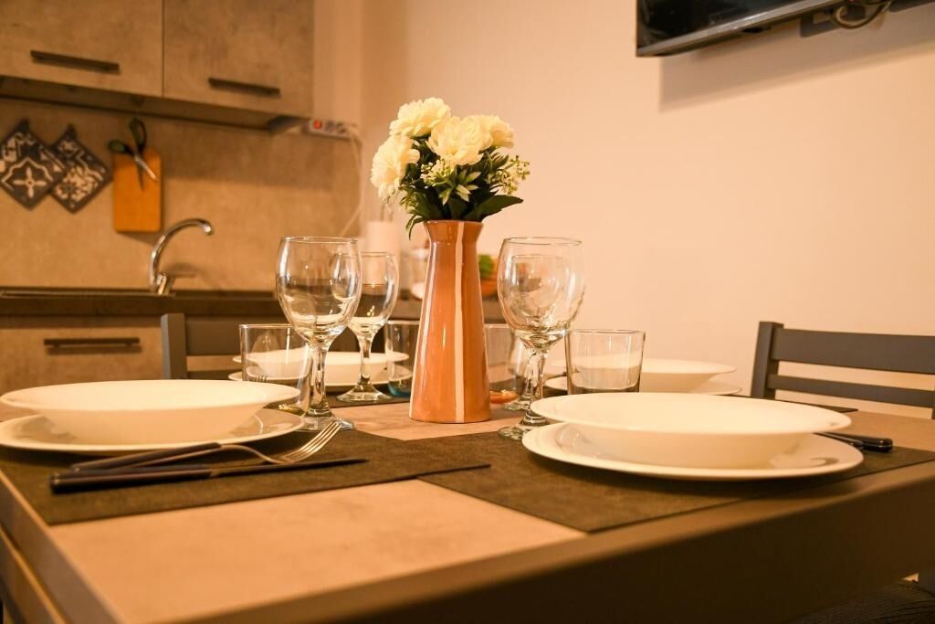 A dining table set with plates, glasses, and a vase of flowers.