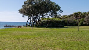 A grassy area with a volleyball net, a bench, and a tree. - Apartment '4 Personne' with Shared Pool, Wi-Fi and Air Conditioning (Cervione)