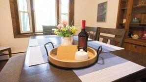 A dining table with a wooden tray, a vase with flowers, and a bottle of wine. - Private Poconos Family Rancher (Albrightsville)