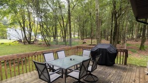 A wooden deck with a glass-top table and chairs, surrounded by a wooden railing. - Private Poconos Family Rancher (Albrightsville)