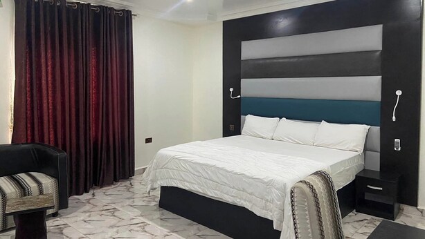 A modern bedroom with a bed, a chair, and a nightstand.