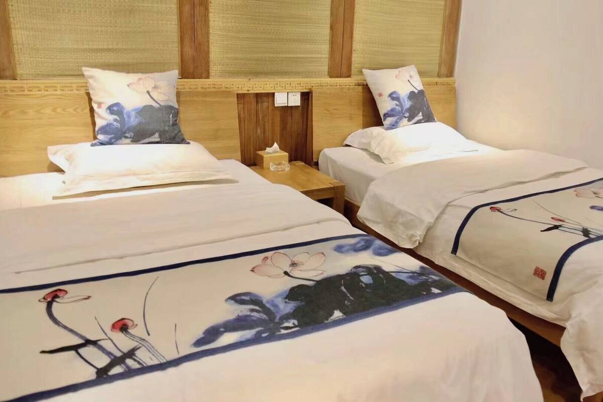 Quarto de hotel com duas camas, cada uma com colcha florida e almofadas combinando.
