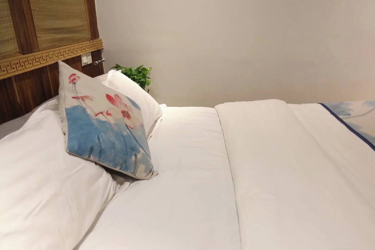 Uma cama bem arrumada com lençóis brancos e almofada estampada com flores.