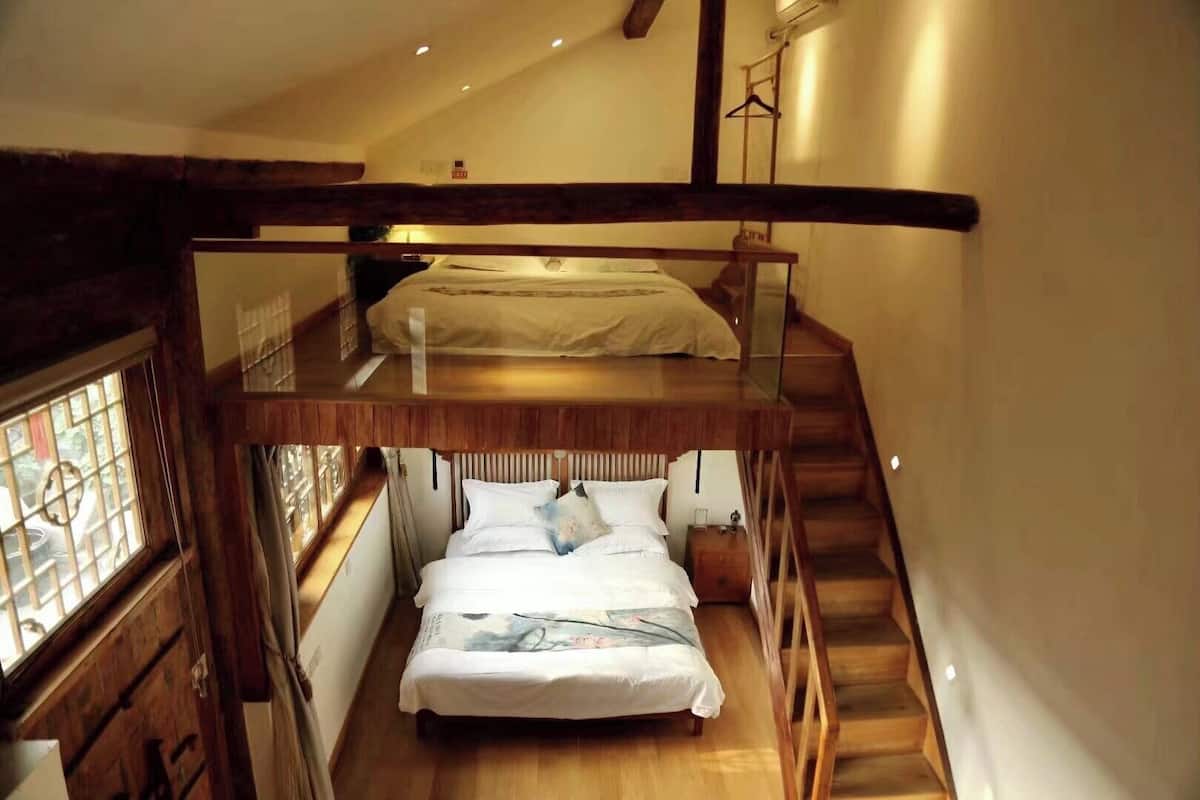 Quarto com beliche, escada de madeira e janela com grades.