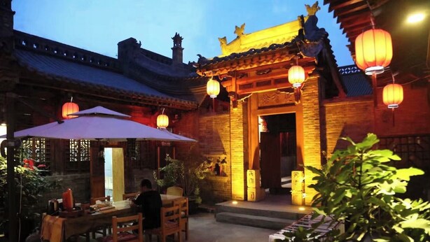 A traditional Chinese courtyard with wooden furniture, lanterns, and a tiled roof. - yunzhikeshepingyaoguchengxianyadian (Jinzhong)