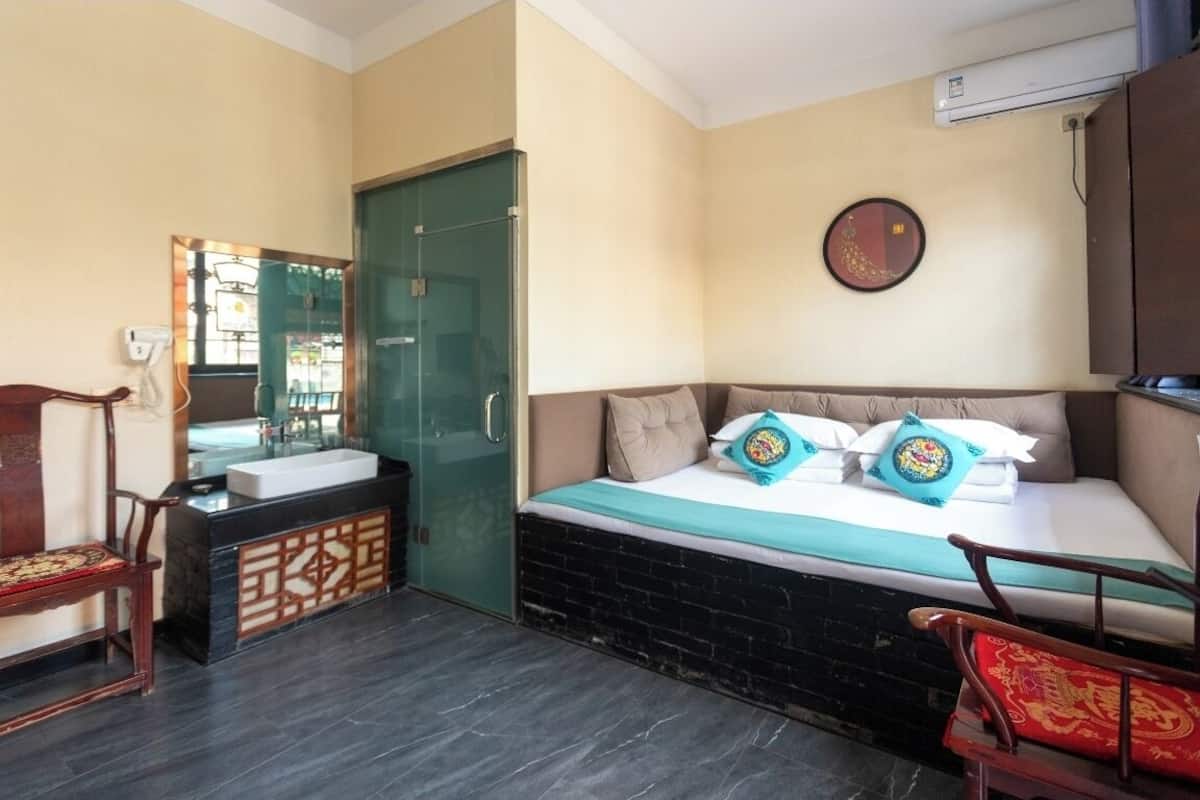 Quarto de hotel com cama, secretária com pia, espelho e guarda-roupa.