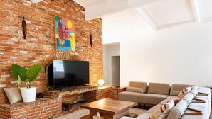 Una sala de estar con chimenea de ladrillo, televisor de pantalla plana, sofá y mesa de centro.