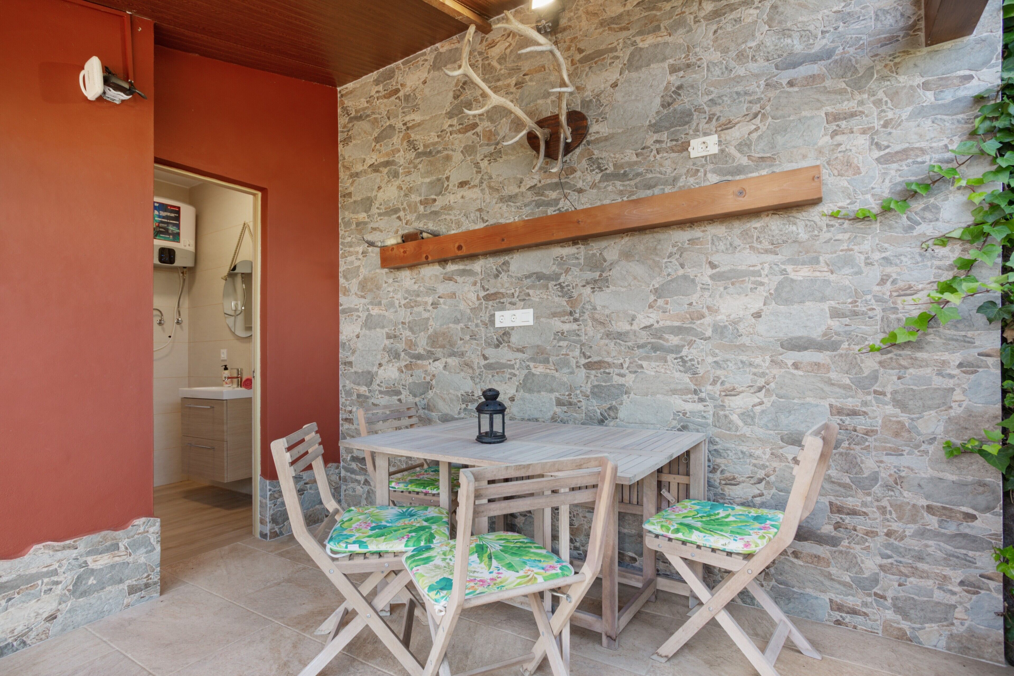 A stone wall, a wooden table with chairs, a hanging light fixture, and a wooden beam.