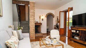 A living room with a sofa, coffee table, fireplace, TV, and a bookshelf. - Charming Tuscany style home with AC and heater in beautiful Umbria. (Umbria)