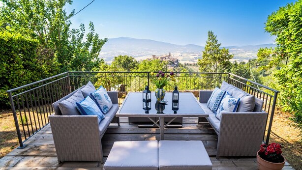 An outdoor patio with wicker furniture, a table, and a view of distant mountains. - Charming Tuscany style home with AC and heater in beautiful Umbria. (Umbria)