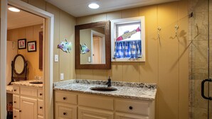 Un baño con tocador, lavabo, espejo y ducha.
