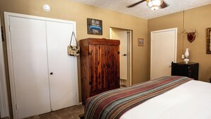 Un dormitorio con una cama, un armario de madera, una puerta y un cartel en la pared.