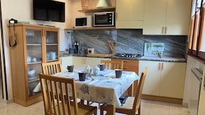A compact kitchen with a dining table, chairs, a microwave, and a stove. - Casa Giorgia welcomes you to the greenery of the Delta with its relaxing quietness (Rosolina)