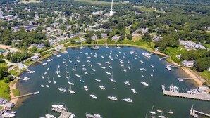Luchtbeeld van een jachthaven met tal van boten die aanmeren, omringd door woonhuizen en groen.