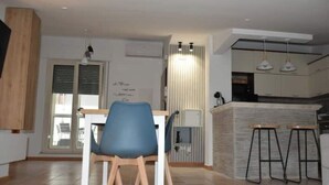 Een moderne keuken met een eethoek, met een houten eettafel, blauwe stoelen en een keukenblok met krukken.