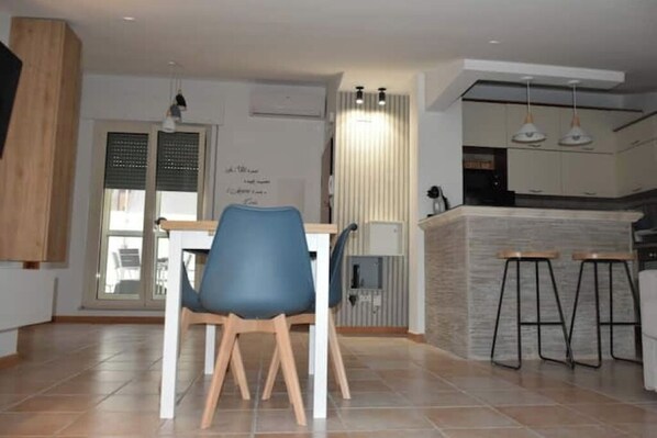 Una cocina moderna con comedor, que incluye una mesa de madera, sillas azules y una isla de cocina con taburetes.