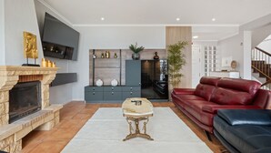 Una sala de estar moderna con chimenea, un sofá de cuero rojo, una mesa de centro de mármol y un televisor de pantalla plana montado en la pared.