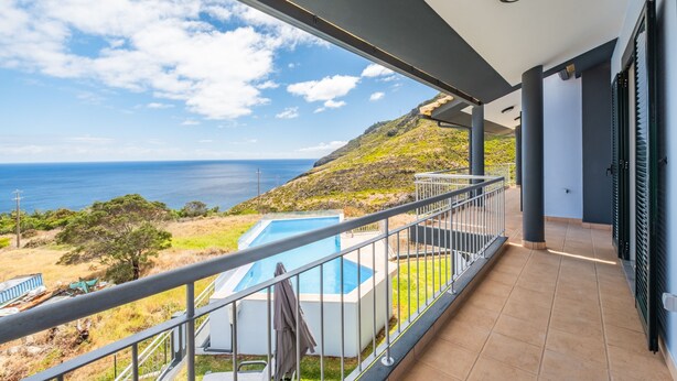 Un balcón con vista al mar y una piscina.