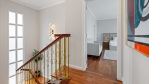 Un interior moderno con una escalera de madera, una cama y un cuadro en la pared.