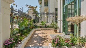 A well-maintained garden pathway leading to a building with large windows and a balcony. - Luxury 4 bedroom Garden View Solar Villa - Tropical Garden Khem Beach (Phu Quoc)