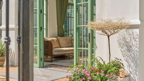 A conservatory with a curved glass door, a cushioned bench, and a planter with flowers. - Luxury 4 bedroom Garden View Solar Villa - Tropical Garden Khem Beach (Phu Quoc)