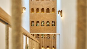 A staircase with wooden steps and a railing, leading to a building with multiple arched windows and a textured wall. - Luxury 4 bedroom Garden View Solar Villa - Tropical Garden Khem Beach (Phu Quoc)