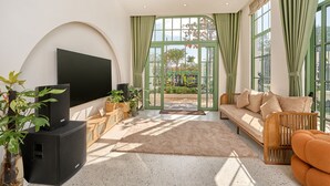 A living room with a TV, sofa, and plants. - Luxury 4 bedroom Garden View Solar Villa - Tropical Garden Khem Beach (Phu Quoc)