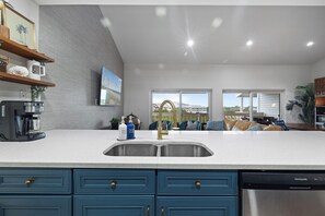 Una cocina moderna con un lavamanos de acero inoxidable, muebles azules y una cafetera.