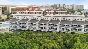 Un hôtel à plusieurs étages doté de balcons, d’une piscine et bordé d’une forêt verdoyante et luxuriante au premier plan.