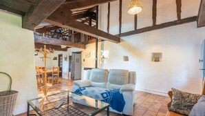 A living room with a sofa, a glass coffee table, and a high ceiling with exposed beams. - Cottage in a Charming Shepherd’s House, Vast Private Land in the Heart of the Pyrenees (CASTET)
