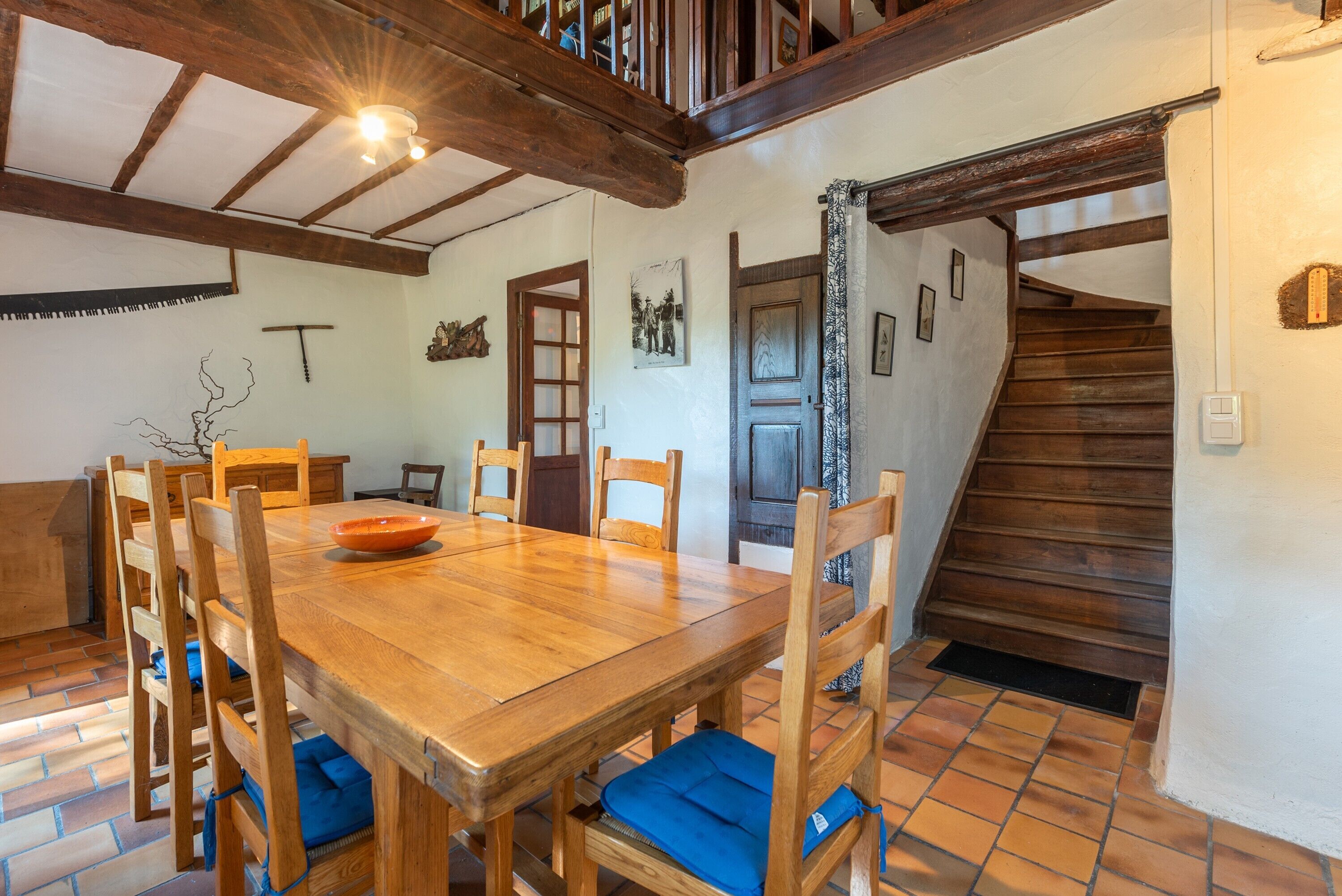 Zona pranzo con tavolo e sedie in legno, una scala e una porta con tenda.