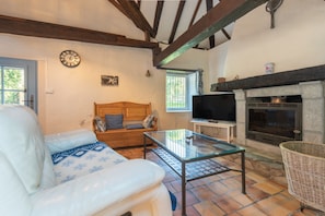 A living room with a sofa, a glass coffee table, a wooden bench, a fireplace, and a television.