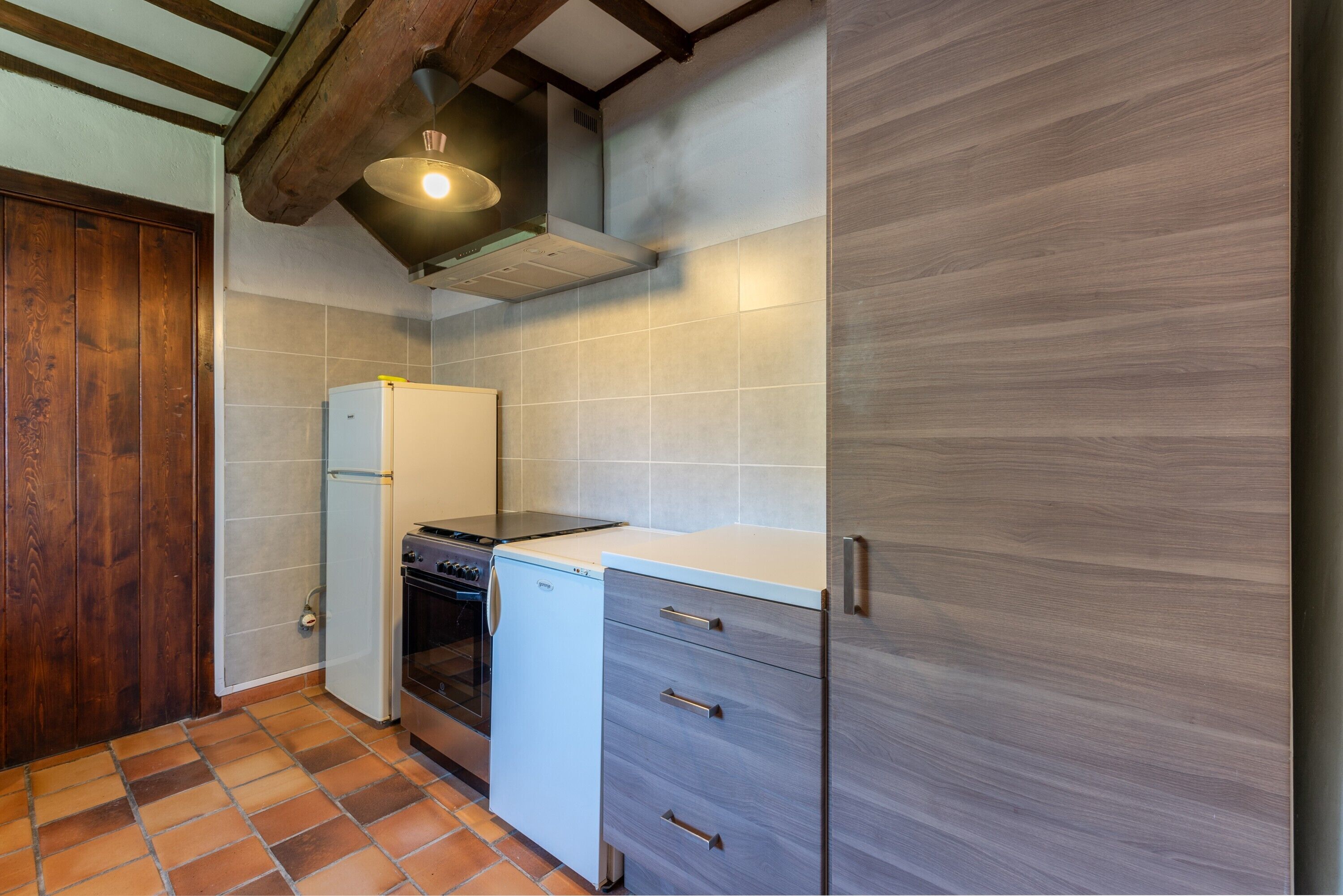 Eine Küche mit Herd, Backofen, Kühlschrank und Holzschränken.