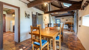 A dining area with a wooden table and chairs, a tiled floor, and exposed wooden beams. - Cottage in a Charming Shepherd’s House, Vast Private Land in the Heart of the Pyrenees (CASTET)