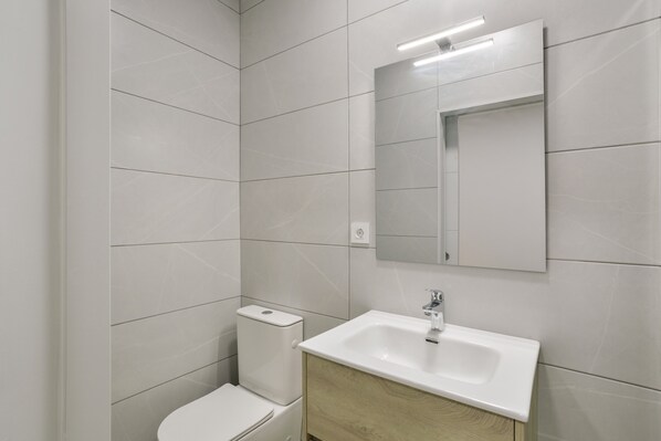 A modern bathroom with a toilet, sink, and mirror.
