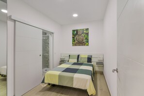 A bedroom with a bed, a nightstand, a wall-mounted artwork, and a sliding door. - Vacation Apartment 'Isleta - Primero A' with Wi-Fi (Las Palmas)