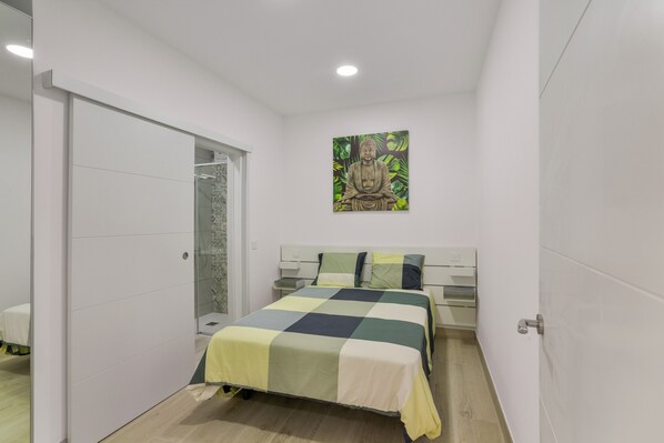 A bedroom with a bed, a nightstand, a wall-mounted artwork, and a sliding door.