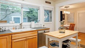 Una cocina con armarios de madera, un fregadero, un lavavajillas y una zona de comedor con una mesa y sillas.